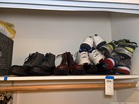 Seven pairs of men's shoes (size 11) on a closet shelf including boots, tennis shoes, and dress shoes in used condition.