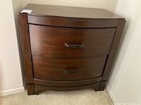 Front view showing the nightstand's two drawers with curved fronts and metal handles.