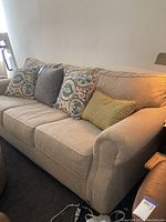 Front angle showing the entire beige sofa with cushions and arm detail