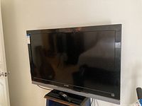 Front view of Sony Bravia 46-inch LED TV with visible screen, brand logo on bottom bezel, and remote control placed on stand below the TV.