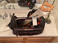 Overall view of the WorkForce tool caddy showing tools including a Great Neck hand saw with wooden handle on top.