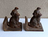 Front angle showing two cast iron puppy dog bookends with aged patina on a white textured surface.