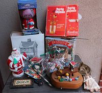 Overall photo of Christmas lot showing porcelain figures, Swedish Party Chimes, Santa figures, garland, and miscellaneous decorations on table.