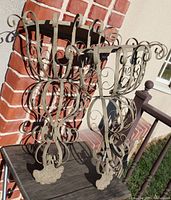 Pair of large wrought iron wall sconces shown outdoors with visible scrollwork and basket-like top sections, showcasing rustic distressed finish.
