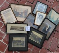 Overall view of the 10 framed items laid on brick ground, showing varied sizes and subjects including portraits, prints and a verse.