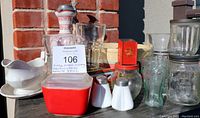Photo showing assortment of vintage kitchen items including red Pyrex container, soda fountain glasses, ironstone gravy boat, salt and pepper shakers, Hershey's jar, and hand-painted pitcher