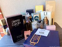 Photo showing multiple boxed and unboxed vintage perfume bottles including Pierre Cardin men's cologne, Sculptura, Chaz, and Via Lanvin.
