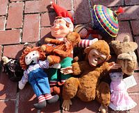 Photo showing assortment of vintage dolls and toys including Raggedy Andy, two stuffed monkeys, other dolls, and metal top