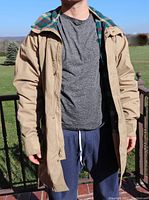 Man wearing the tan vintage Woolrich jacket outdoors, showing length and fit, open zipper with visible flannel lining, and sleeves.