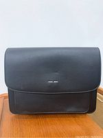 Front view of black Pixie Mood handbag with flap closure and silver logo.
