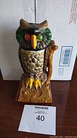 Front view of the antique cast iron owl mechanical coin bank showing painted details and plastic eyes.
