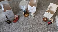 Three Santa Claus incense burner figures with their original boxes and round wooden incense holders placed on carpet.