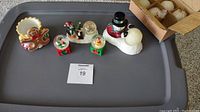 Top view of all six Christmas items on a tray showing gingerbread cupcake votive holder, snow globes, and snowman with candles.