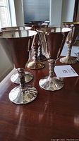 Photo of eight silver plated wine cocktail cups showing twisted stems, reflective surfaces with some tarnish, and rounded bases.