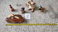 Full view of seven small collectibles arranged on carpet next to measuring tape