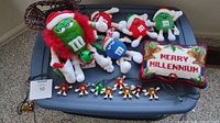 Overview of all items including M&M's stuffed characters, pillow, sleigh and light string on a plastic bin lid