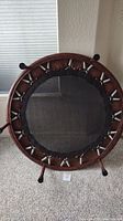 Top view of mini trampoline showing springs and brown padded vinyl edge with black rubber leg caps.