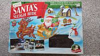 Box artwork featuring colorful illustration of Santa's sleigh ride and details of the product.