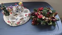 Photo showing the ceramic snowmen tea light holder and the small candle ring side by side on a plastic surface.