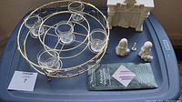 Top view of bronze circular Advent wreath with five glass candle holders, four-piece white ceramic hearth scene including fireplace and two polar bears, Christmas candles box visible.