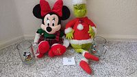Photo showing Minnie Mouse and Grinch stuffed toys along with two vintage Disney mugs on the floor.