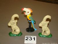 Front view of two cast iron rams and one parrot bottle opener against a brown background with lot number