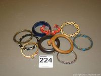 Overview of all 10 assorted bracelets and bangles arranged on a flat surface, showing various colors and materials including wood, metal, resin, and stones.