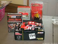 Photo of collection showing NASCAR car model on box, DVD, figure in packaging, and a collector's card pack