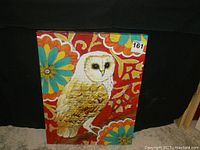 Full view of the colorful owl canvas print against a black backdrop.