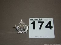 Silver-toned police pin featuring a maple leaf with the word 'POLICE'.