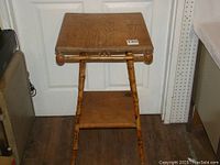 Full view of vintage decorative small table showing bamboo-style legs, square wooden top, and lower shelf.