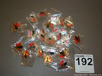 Pile of 25 Team Canada hockey lapel pins in individual clear plastic bags showing the maple leaf, hockey player silhouette, and 'CANADA' text.