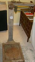 Full view of the vintage mechanical balance scale showing the wooden platform base and upright support with balance beam on top.