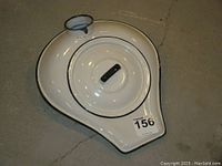 Top view of vintage enamelware bedpan urinal with lid showing black handle and spout detail.