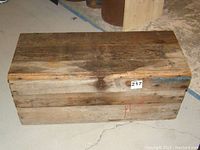 Closed wooden box showing aged wood with metal latch and seller lot number sticker.