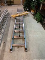 Full view of ladder laid out on floor with stabilizer box on top
