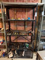 Full view of metal shelving unit loaded with assorted hand tools and small containers on shelves.