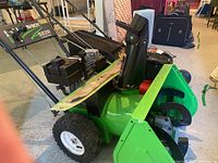 Right-side view of snow blower showing green auger housing and black steel auger blades