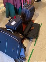 Photo showing the four luggage pieces arranged on the floor including two upright carry-ons, one black soft-sided bag, and another padded carry-on.