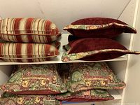 Photo of six pillows on shelves: two striped, two burgundy velvet with floral trim, four floral pattern pillows below