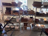 Front view of the white metal three-tier shelving unit filled with various woven baskets on all shelves, in an indoor setting with concrete floor and window light.