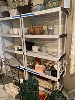 Two tall plastic shelving units placed side by side holding various flower pots and garden decor.