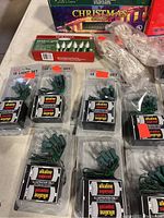 Photo of 12 battery-powered 12-light sets in packaging showing alkaline supercell batteries and bulbs with green wiring, along with a box of 50 mini white lights.