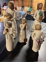 Photo showing all five Willow Tree figurines arranged on a surface. Includes the Mother and Son, Angel holding pineapple, and others together.
