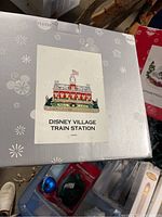 Photo of Disney Village Train Station box with logo and red, white, and blue building image.