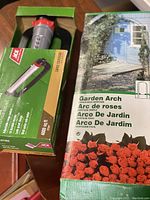 Box of the garden arch with rose design showing outdoor setting graphic and product name in multiple languages.