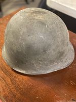 Photo of the helmet outer surface showing wear and matte green paint.