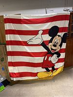 Full view of the large fabric banner showing Mickey Mouse against red and white stripes