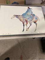 Full view of the framed Native American art print showing a woman in a blue robe riding a horse.