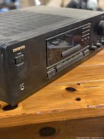 Left side view of Onkyo TX-8211 receiver showing power button, headphone jack, display panel, and various input buttons.
